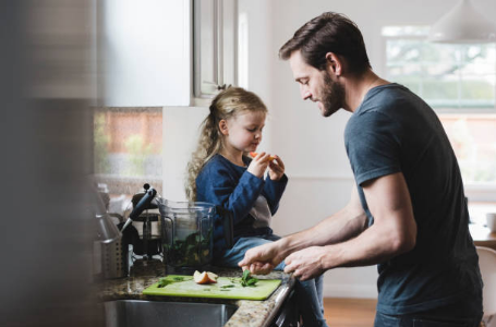 homme qui prépare à manger avec sa fille assise sur le comptoir à côté